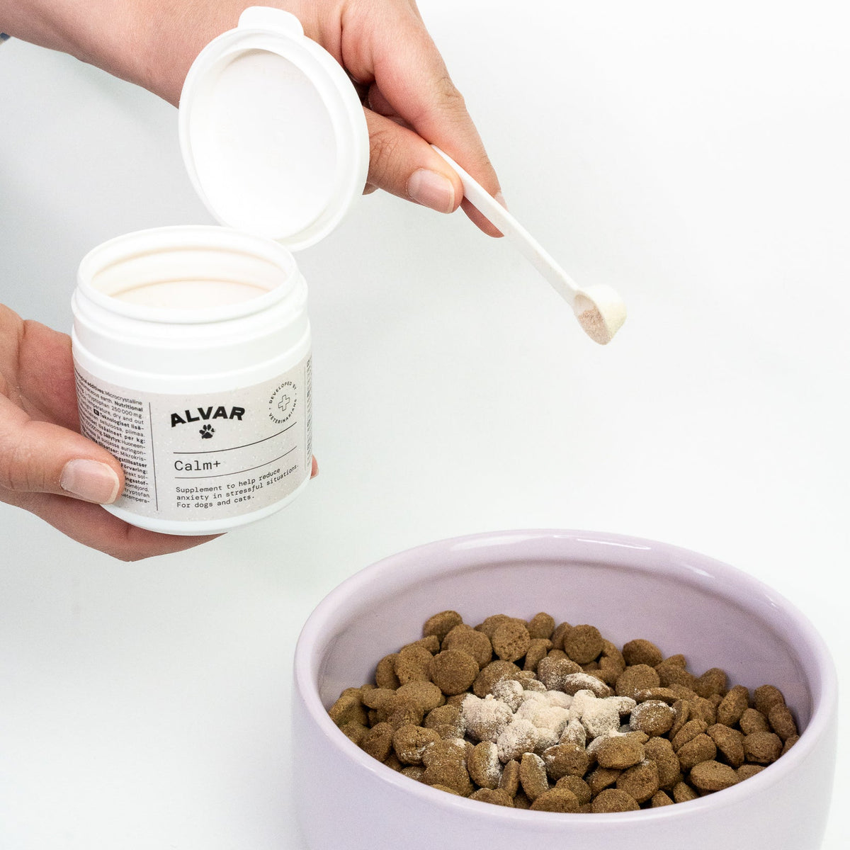 Person adding Calm+ supplement into a bowl of pet food.